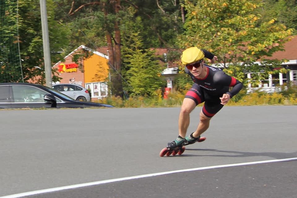 Emil Nielsen in a low racing tuck on inline skates, mid-stride on an outdoor track